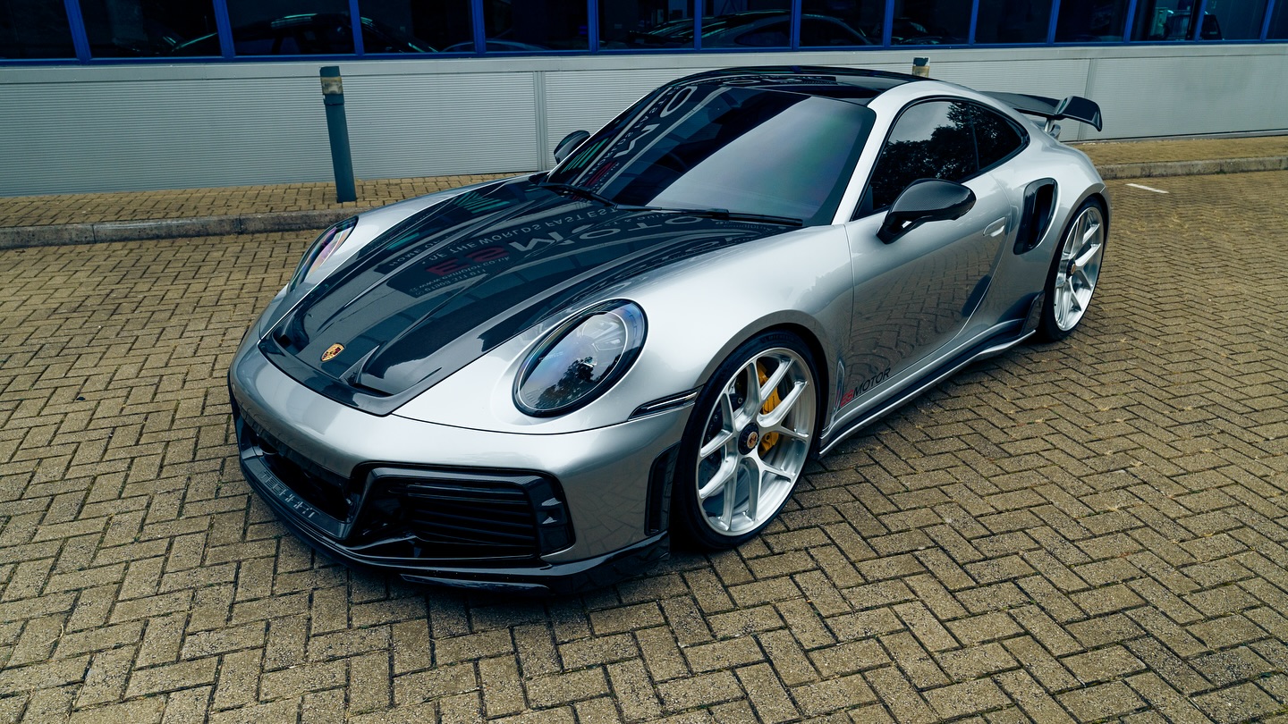 Silver Porsche sports car on brick pavement.