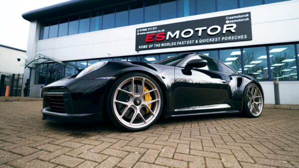 Black Porsche sports car parked in front of ESMotor building.