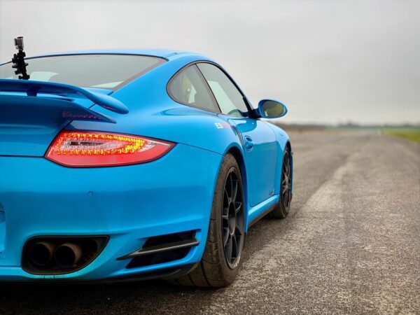 Rear view of a blue Porsche on an empty road