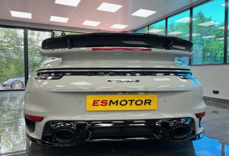 Rear view of a white Porsche 911 Turbo S with yellow ESMOTOR license plate.