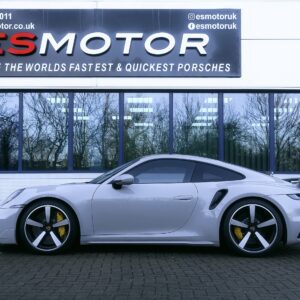 Side view of a silver Porsche parked in front of ESMotor building.