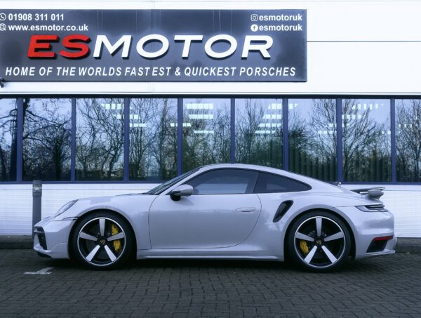 Side view of a silver Porsche parked in front of ESMotor building.