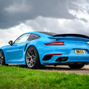 Blue Porsche ES1500 parked on a road with a cloudy sky in the background.