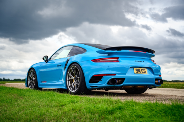 Blue Porsche ES1500 parked on a road with a cloudy sky in the background.