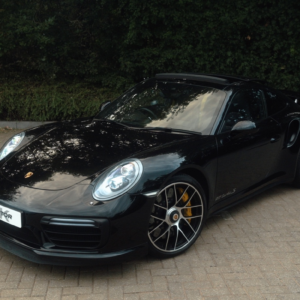 Black Porsche ES650 parked on a paved surface with greenery in the background.