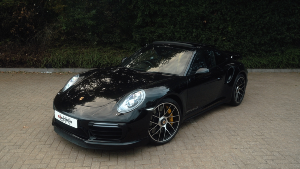 Black Porsche ES650 parked on a paved surface with greenery in the background.