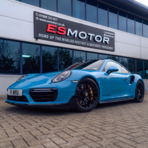 Blue Porsche ES800 in front of ESMotor building with large windows.