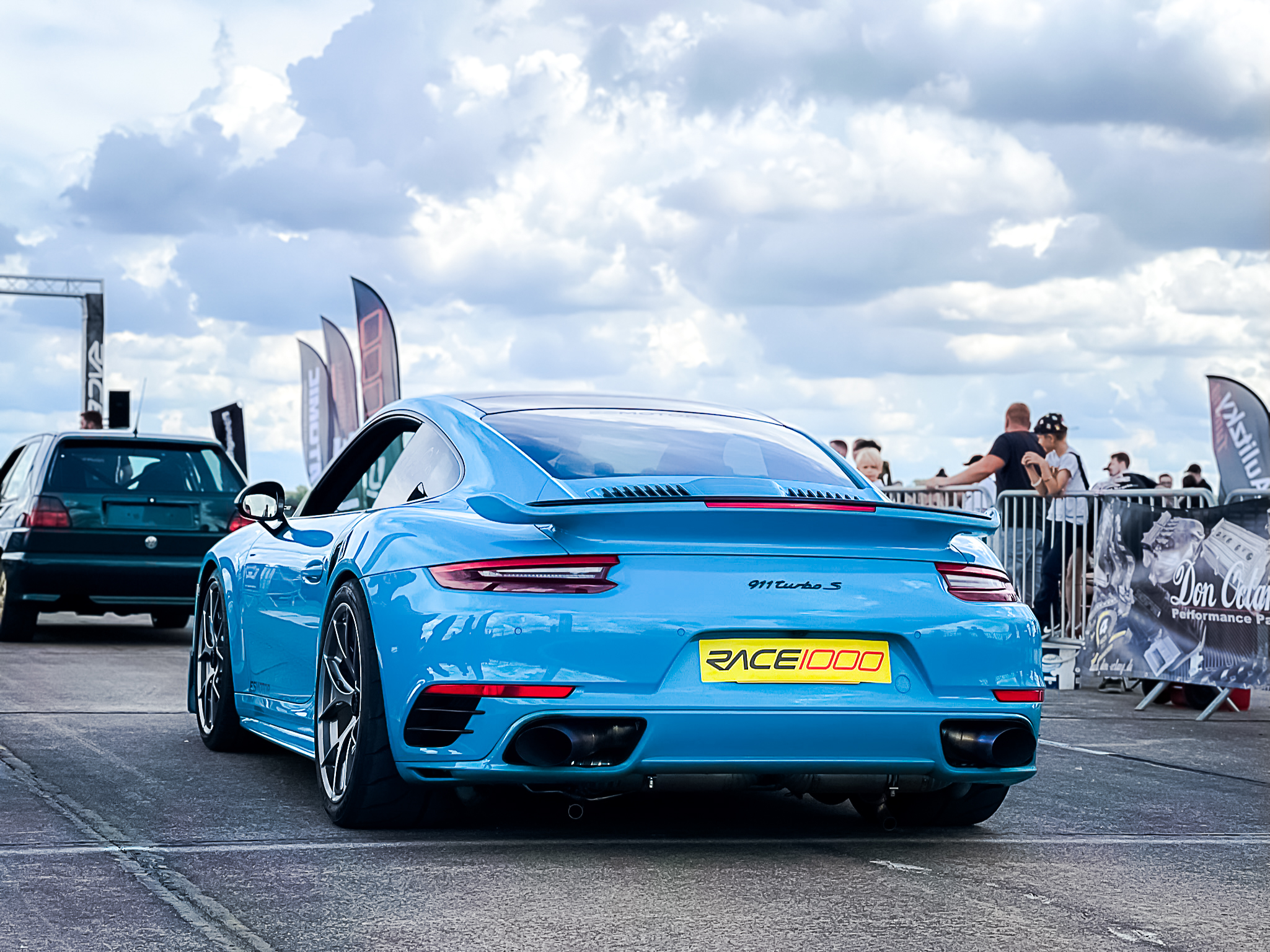 Rear view of a blue Porsche 911 Turbo S at a car event.