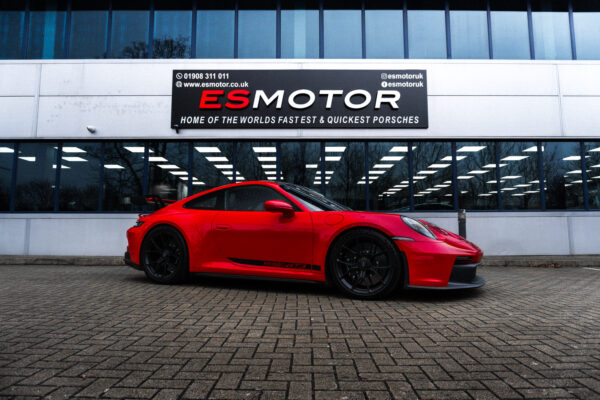 Red Porsche parked in front of ESMotor building.