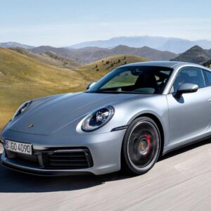 Silver Porsche 911 driving on a scenic road with hills.